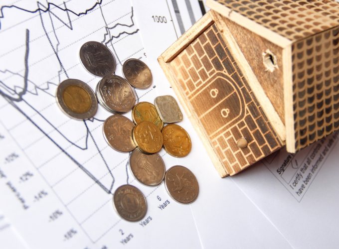 A small home on financial report with different currencies. Financial diagram is showing ups and downs in business. This photo can use as Financial background.